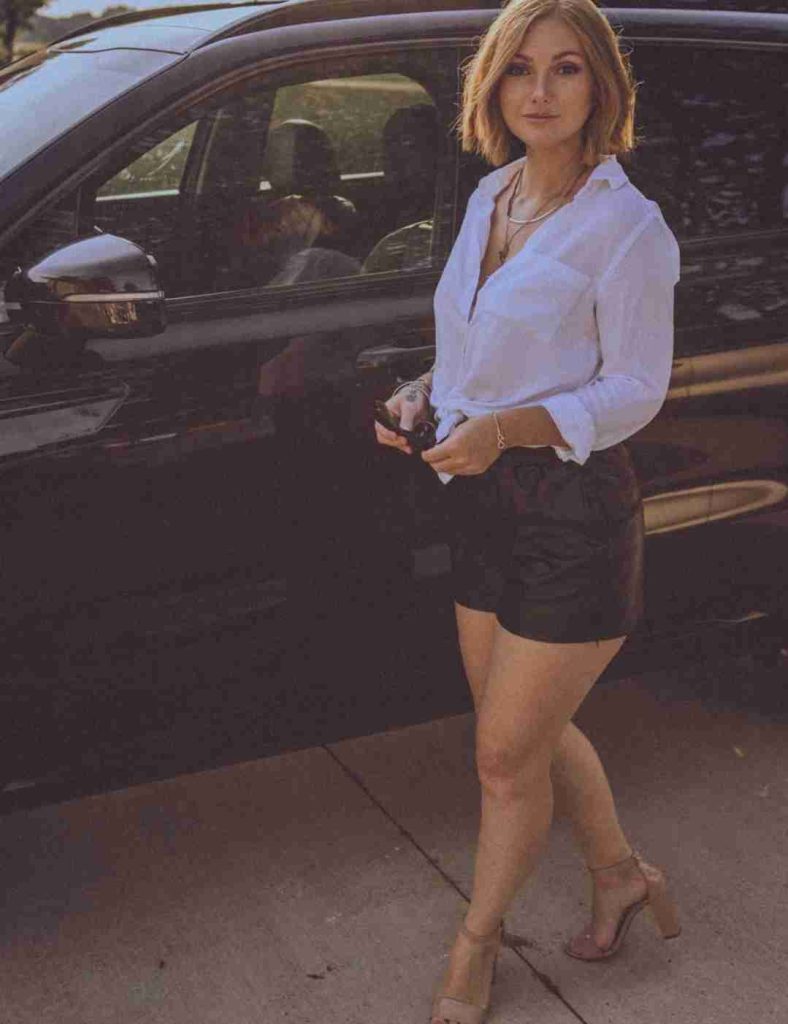 A photo of Natalie Lust standing beside her car